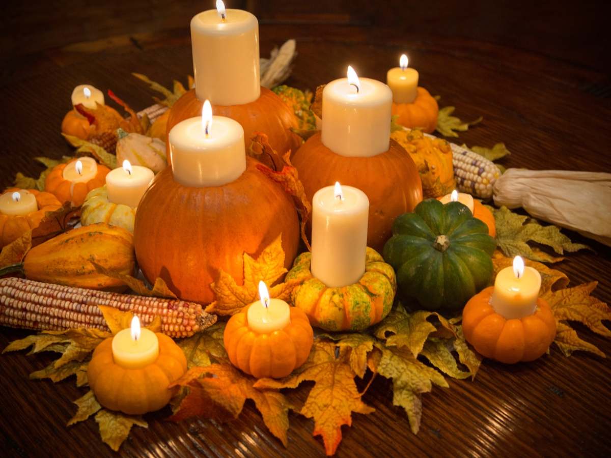 A charming display of pumpkin-themed candles amidst a bed of fall leaves and gourds is captured in the fourth photo offering an imaginative and festive centerpiece idea that encapsulates the essence of Thanksgiving
